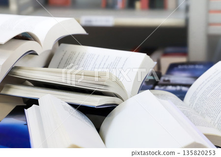 stack of books, close up. Open book on the table in library. Back to school concept. Open book on table with blur bookshelf background stack of books, close up. Open book on the table in library. Back to school concept. Open book on table with blur bookshelf background 135820253