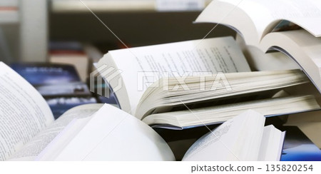 stack of books, close up. Open book on the table in library. Back to school concept. Open book on table with blur bookshelf background stack of books, close up. Open book on the table in library. Back to school concept. Open book on table with blur bookshelf background 135820254