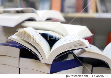 stack of books, close up. Open book on the table in library. Back to school concept. Open book on table with blur bookshelf background stack of books, close up. Open book on the table in library. Back to school concept. Open book on table with blur bookshelf background 135820255