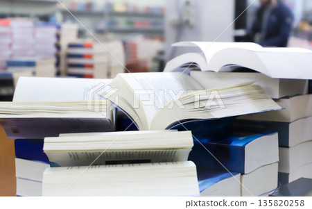 stack of books, close up. Open book on the table in library. Back to school concept. Open book on table with blur bookshelf background stack of books, close up. Open book on the table in library. Back to school concept. Open book on table with blur bookshelf background 135820258