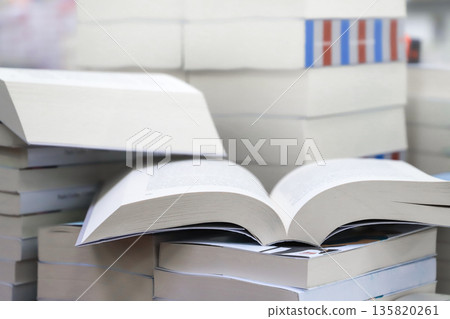 stack of books, close up. Open book on the table in library. Back to school concept. Open book on table with blur bookshelf background stack of books, close up. Open book on the table in library. Back to school concept. Open book on table with blur bookshelf background 135820261