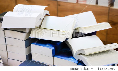 stack of books, close up. Open book on the table in library. Back to school concept. Open book on table with blur bookshelf background stack of books, close up. Open book on the table in library. Back to school concept. Open book on table with blur bookshelf background 135820269