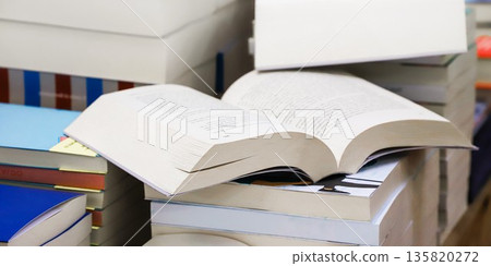 stack of books, close up. Open book on the table in library. Back to school concept. Open book on table with blur bookshelf background stack of books, close up. Open book on the table in library. Back to school concept. Open book on table with blur bookshelf background 135820272