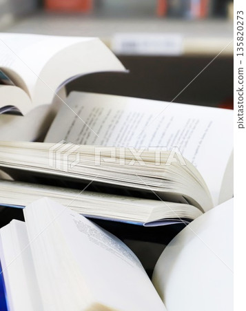 stack of books, close up. Open book on the table in library. Back to school concept. Open book on table with blur bookshelf background stack of books, close up. Open book on the table in library. Back to school concept. Open book on table with blur bookshelf background 135820273