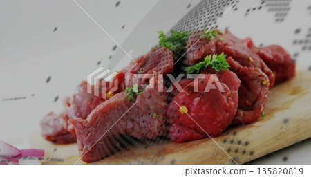 Lying raw beef chunks on wooden cutting board in kitchen with parsley, cracked pepper, onion slices 135820819