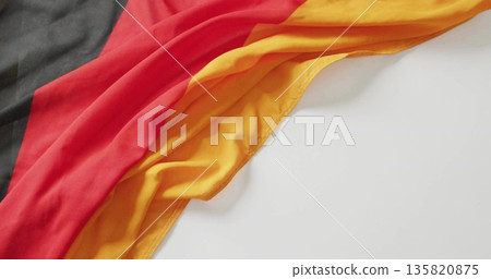 Draping tricolor cloth displaying black red yellow stripes on smooth white surface, copy space 135820875