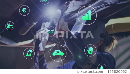 Operating gloved technician grinding chassis with grinder at workshop, with CO? and currency icons 135820962