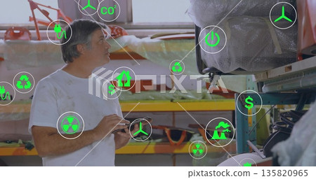 Inspecting technician holding tablet in warehouse, with wrapped boat hull, energy icons, copy space Inspecting technician holding tablet in warehouse, with wrapped boat hull, energy icons, copy space 135820965