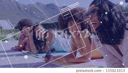 Four friends in swimwear lying and chatting on pool deck, with towels, sunglasses, network overlay 135821013