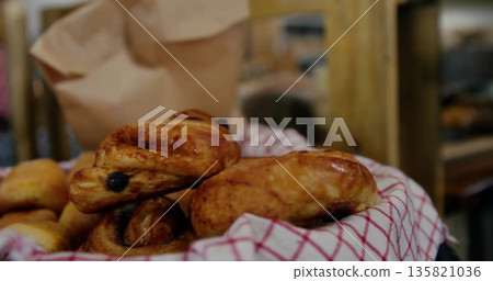 Displaying wicker basket filled with raisin pastries on bakery counter with red-and-white cloth Displaying wicker basket filled with raisin pastries on bakery counter with red-and-white cloth 135821036