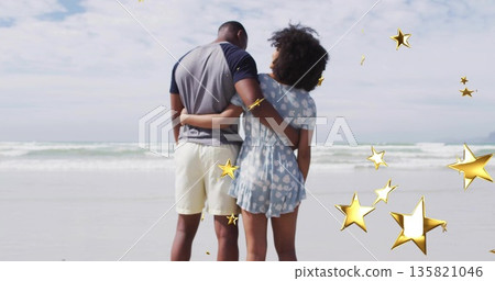 Couple in casual beachwear embracing on sandy beach, with golden stars floating above ocean waves Couple in casual beachwear embracing on sandy beach, with golden stars floating above ocean waves 135821046