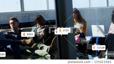 Waiting passengers using laptops and tablet on lounge chairs in airport gate, with AR notifications 135821083