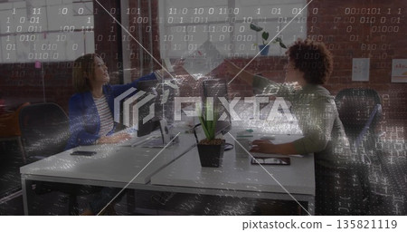 Fist bumping woman and man celebrating work in open-plan office, with dual monitors and succulent Fist bumping woman and man celebrating work in open-plan office, with dual monitors and succulent 135821119