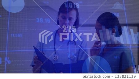 Clinicians wearing blue scrubs analyzing digital charts in clinic room, with clipboard stethoscope Clinicians wearing blue scrubs analyzing digital charts in clinic room, with clipboard stethoscope 135821139
