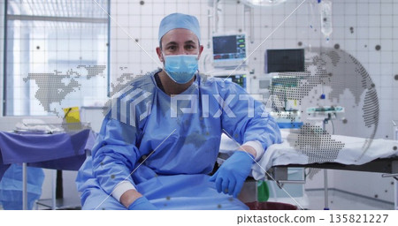Sitting surgeon wearing scrubs on table edge at operating room with vital monitor, map overlay 135821227