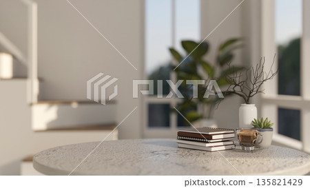 Round marble table with books and a glass of coffee aside potted plant in a modern house or building Round marble table with books and a glass of coffee aside potted plant in a modern house or building 135821429