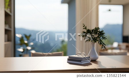Vase and glasses atop book on wooden table in a room with window wall and mountain scenery terrace. Vase and glasses atop book on wooden table in a room with window wall and mountain scenery terrace. 135821544