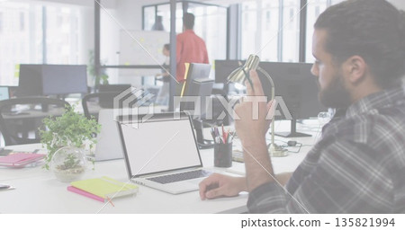 Adjusting lamp, male in plaid shirt sitting at office desk with open laptop, terrarium, copy space 135821994