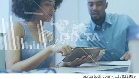 Collaborating professionals analyzing chart on tablet in conference room, with laptop and coffee 135821999