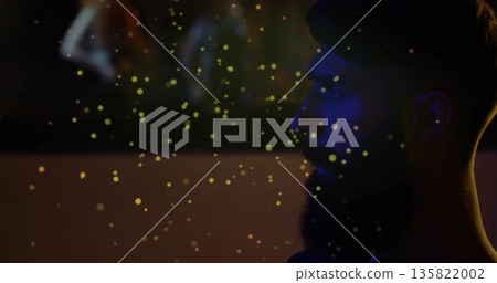 Gazing bearded man observing golden particles drifting in studio, with blurred figures copy space Gazing bearded man observing golden particles drifting in studio, with blurred figures copy space 135822002