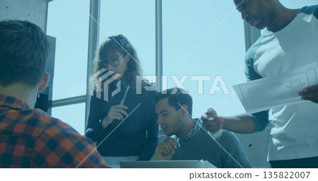 Collaborating group of four colleagues reviewing schematic and laptop in modern office, with pen 135822007