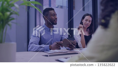 Man leading team holding tablet at table in meeting room, with pens, clipboards and potted plant Man leading team holding tablet at table in meeting room, with pens, clipboards and potted plant 135822022