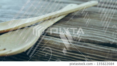 Showing two wooden spatulas overlapping diagonally on rustic wooden countertop, with data charts 135822084