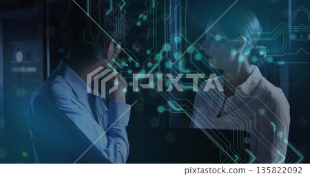 Discussing IT professionals analyzing data flow in server room with open laptop, circuitry overlay Discussing IT professionals analyzing data flow in server room with open laptop, circuitry overlay 135822092