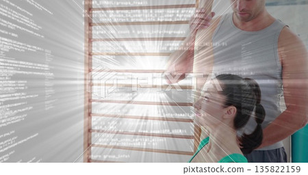 Male trainer guiding female client in shoulder stretch in gym, with wooden rod, code overlay 135822159