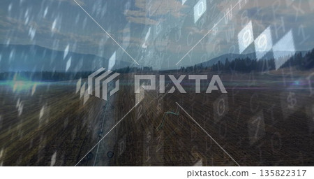 Moving irrigation boom across plowed rows on farm with pine mountains, clouds, digital code overlay 135822317