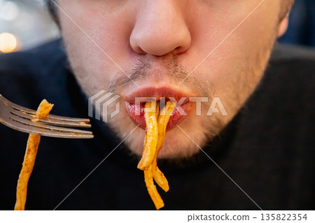 man eats fat pasta, sucks it with his mouth showcasing overeating and unhealthy eating habits. concept of obesity, diabetes, gluttony, diabetes, overeating, close-up of his chewing mouth 135822354