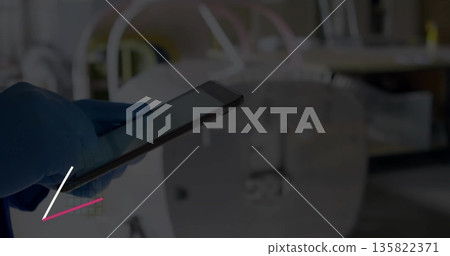 Holding tablet computer with gloved hand in radiology suite, with blurred scanner, copy space 135822371