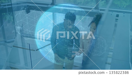 Descending two professionals conversing in modern atrium, with holographic globe and glass railing 135822386