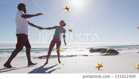 Spinning couple holding hands in casual summer clothes on sunlit beach, with gold star overlays Spinning couple holding hands in casual summer clothes on sunlit beach, with gold star overlays 135822400