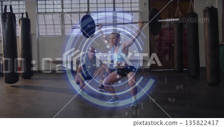 Athlete in gear performing overhead barbell squat in gym, with coach guiding and HUD overlay Athlete in gear performing overhead barbell squat in gym, with coach guiding and HUD overlay 135822417