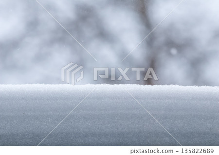 Fresh snow building up on a surface during winter with blurred trees in background creating a clean copy space 135822689