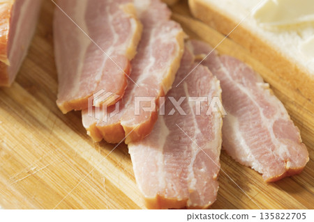 Dried smoked chicken breast cut into pieces for sandwiches. Smoked bacon with layers of meat and with bread and butter on the wood desk. The pieces of pork brisket for breakfast or lunch. Dried smoked chicken breast cut into pieces for sandwiches. Smoked bacon with layers of meat and with bread and butter on the wood desk. The pieces of pork brisket for breakfast or lunch. 135822705