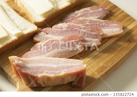 Dried smoked chicken breast cut into pieces for sandwiches.Smoked bacon with layers of meat and with bread and butter on the wood desk. The pieces of pork brisket for breakfast or lunch. 135822724