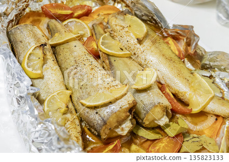 Spiced hake baked in the oven with lemon, tomatoes, carrots, and onions in foil. Delicious fish for lunch or dinner, perfect for a diet. Tasty hake fish baked with vegetables. Spiced hake baked in the oven with lemon, tomatoes, carrots, and onions in foil. Delicious fish for lunch or dinner, perfect for a diet. Tasty hake fish baked with vegetables. 135823133