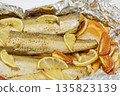Spiced hake baked in the oven with lemon, tomatoes, carrots, and onions in foil. Delicious fish for lunch or dinner, perfect for a diet. Tasty hake fish baked with vegetables. 135823139