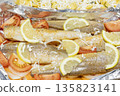 Prerape raw spiced hake for a bake in the oven with lemon, tomatoes, carrots, and onions in foil. Delicious fish for lunch or dinner, perfect for a diet. Tasty and fresh  hake fish for bake with 135823141