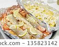 Prerape raw spiced hake for a bake in the oven with lemon, tomatoes, carrots, and onions in foil. Delicious fish for lunch or dinner, perfect for a diet. Tasty and fresh  hake fish for bake with 135823142