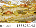 Spiced hake baked in the oven with lemon, tomatoes, carrots, and onions in foil. Delicious fish for lunch or dinner, perfect for a diet. Tasty hake fish baked with vegetables. 135823148