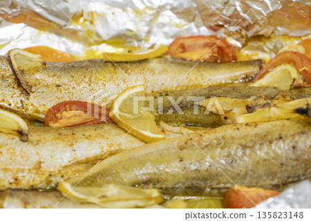 Spiced hake baked in the oven with lemon, tomatoes, carrots, and onions in foil. Delicious fish for lunch or dinner, perfect for a diet. Tasty hake fish baked with vegetables. Spiced hake baked in the oven with lemon, tomatoes, carrots, and onions in foil. Delicious fish for lunch or dinner, perfect for a diet. Tasty hake fish baked with vegetables. 135823148