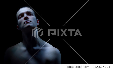 Male portrait looking up with strong contrast lighting. Male portrait looking up with strong contrast lighting. 135823793