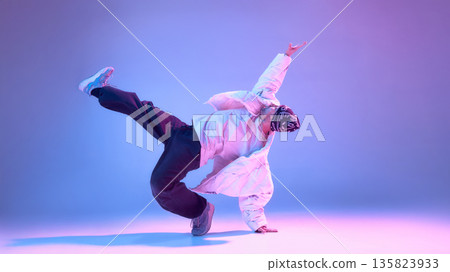 Male hip hop dancer balancing on one hand with extended leg in studio. Male hip hop dancer balancing on one hand with extended leg in studio. 135823933