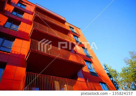 Facade building. Modern brick building with windows on blue sky and bright colors during day. 135824157