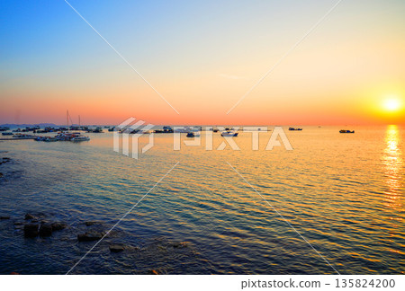 Fishing boat in sea on sunset. Sunset over ocean, casting orange and pink colors in sky. Fishing boat in sea on sunset. Sunset over ocean, casting orange and pink colors in sky. 135824200
