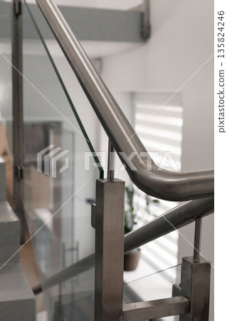 A stylish staircase showcases sleek stainless steel handrails and glass panels. The modern design complements the light-filled space, enhancing overall aesthetics and functionality A stylish staircase showcases sleek stainless steel handrails and glass panels. The modern design complements the light-filled space, enhancing overall aesthetics and functionality 135824246