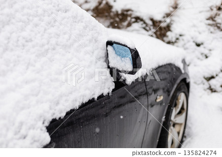 A parked car sits in a residential area with a thick layer of snow covering the roof and side mirror. It is daytime and snowflakes continue to fall A parked car sits in a residential area with a thick layer of snow covering the roof and side mirror. It is daytime and snowflakes continue to fall 135824274
